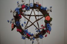 a wicker pentagram with flowers and leaves hanging from the side of a door