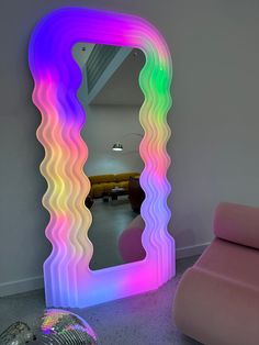 a mirror that is sitting on the floor in front of a pink chair and couch