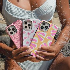 a woman holding three cell phones in front of her face, with water splashing around her