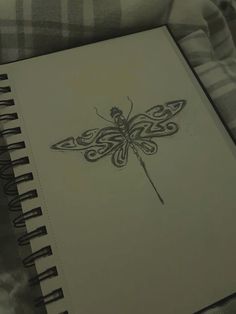 a drawing of a dragonfly sitting on top of a white book next to a plaid blanket