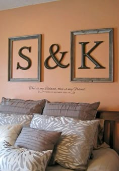 a bed with two framed pictures above it and the word s & k on the wall