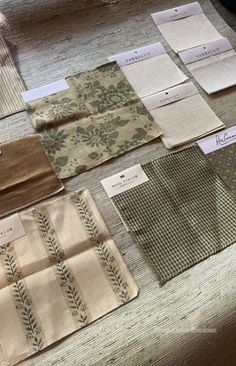 some fabric samples are on a table with tags and labels in front of them,