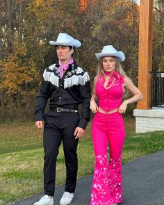 a man and woman in cowboy hats standing next to each other on a paved path