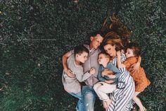 a group of people laying on top of each other in front of green grass and bushes