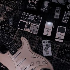 an electric guitar, pedals and other electronic devices laid out on a carpeted area