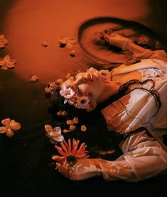 a woman laying on the ground next to flowers