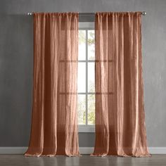 an orange curtain hanging on the side of a window in front of a gray wall