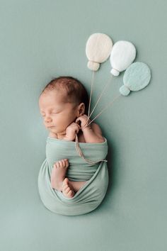 a newborn baby is wrapped in a blanket with balloons attached to it's head