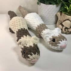 two crocheted stuffed animals sitting on top of a table next to a potted plant