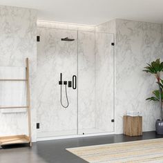 a bathroom with marble walls and flooring next to a plant in a vase on the floor