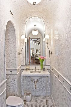 a white toilet sitting next to a sink in a bathroom under a light above it