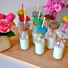 a wooden table topped with lots of cupcakes and donuts covered in sprinkles