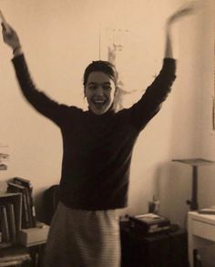 an old photo of a woman holding her arms up in the air and smiling at the camera