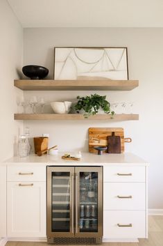 a kitchen with two wine coolers on top of the cabinets and shelves above it