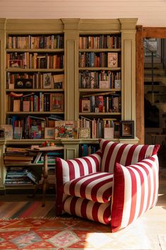 a living room filled with lots of furniture and bookshelves covered in red and white striped pillows