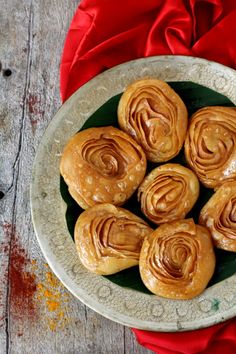 a white plate topped with pastries on top of a red cloth covered wooden table