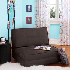 a black futon bed sitting on top of a wooden floor next to a window