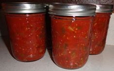 four jars filled with food sitting on top of a counter