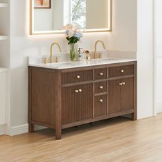 a bathroom vanity with two sinks and a large mirror over the sink that has lights on it