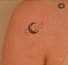 a small tattoo on the back of a woman's shoulder with an image of saturn