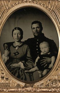 an old black and white photo of two people holding a baby