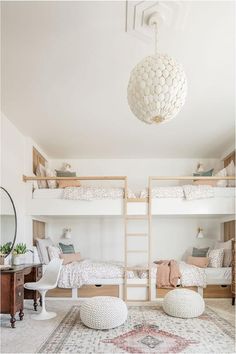 a white bedroom with bunk beds and pillows on the bottom floor, in front of a mirror