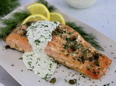 a piece of salmon on a plate with sour cream sauce