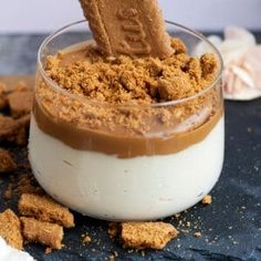 a dessert in a small glass bowl with graham crackers on the side and a spoon sticking out of it