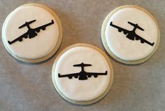 three decorated cookies with black and white icing depicting an airplane on the top one