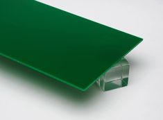 a close up of a green plastic table top on a white surface with an object in the background