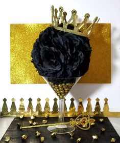 a black rose in a wine glass surrounded by gold and silver confetti pieces