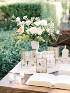 an open book on a table with pictures and flowers in vases next to it