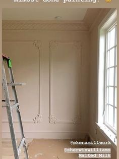 a ladder is in the middle of a room with white walls and paint on it