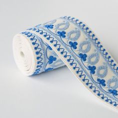 a roll of blue and white patterned ribbon on a white tablecloth with an intricate design