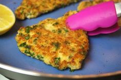 crab cakes with lemon wedges on a blue plate next to a pink spatula