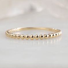 The Gold Beaded Stacking Ring in 14K Yellow Gold on White Marble Plain Gold Wedding Bands, Beaded Stacking Rings, Simple Wedding Band, Watermelon Tourmaline Ring, Birthstone Stacking Rings, Simple Wedding Bands, Stackable Wedding Bands, Custom Wedding Band, Black Diamond Engagement