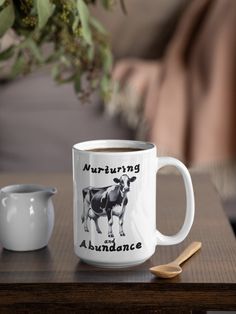 there is a coffee cup with a cow on it and a spoon next to it