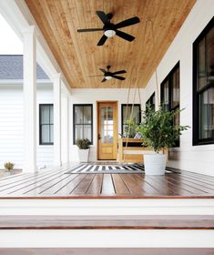 a porch with wooden flooring and ceiling fans on the ceiling, along with potted plants