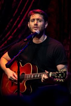 a man holding a guitar in front of a microphone