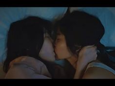 two women laying in bed kissing each other