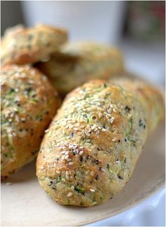 three bread rolls on a plate with sprinkled seeds