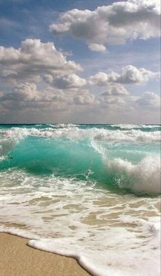 waves crashing on the beach with blue sky and clouds