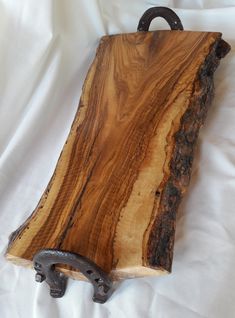 a wooden cutting board with iron handles on a white cloth covered tablecloth or bed sheet