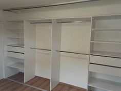 an empty walk in closet with white walls and shelves, wood flooring on the side