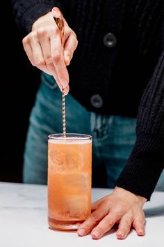 a person holding a straw in front of a drink