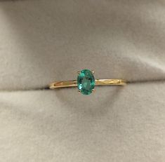 a ring with a green stone sitting on top of a white cloth covered tablecloth