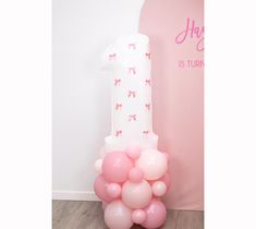 a number one balloon sitting on top of a table next to a pink wall and floor