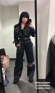 a woman taking a selfie in front of a mirror wearing black clothing and boots