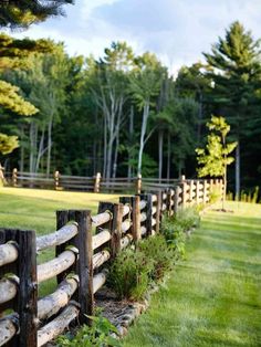 a wooden fence in the middle of a grassy field