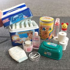 an assortment of toiletries and baby products on a table with someone's hand